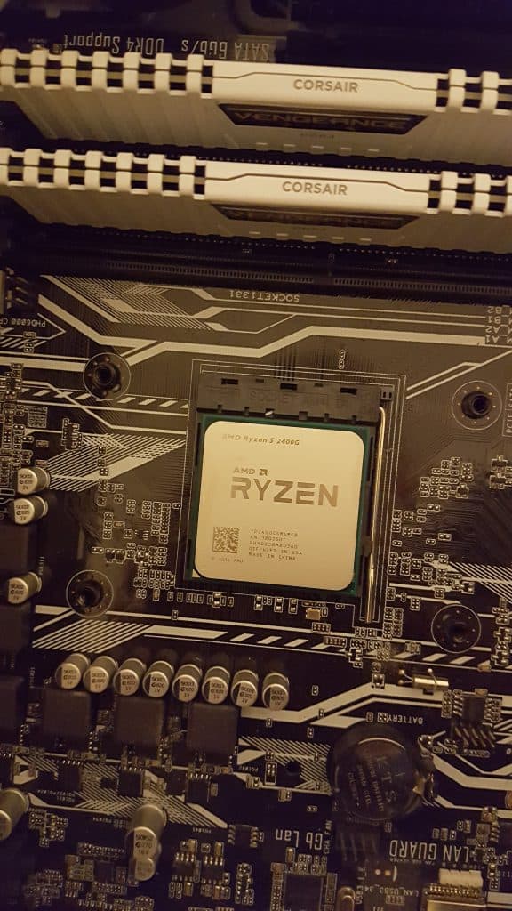 A AMD Ryzen 5 2400G APU CPU with included graphics chip installed on my Asus motherboard with two Corsair RAM sticks shown