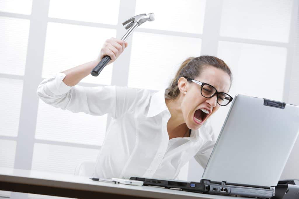 A woman rage quitting and hitting her laptop with a hammer