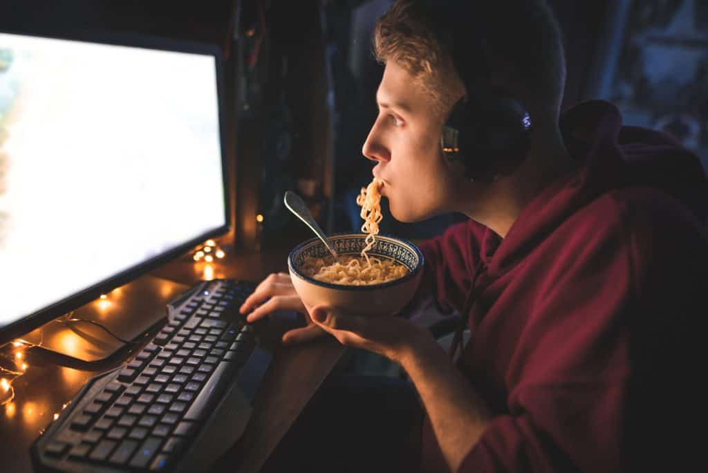 Someone eating noodle soup while on a PC